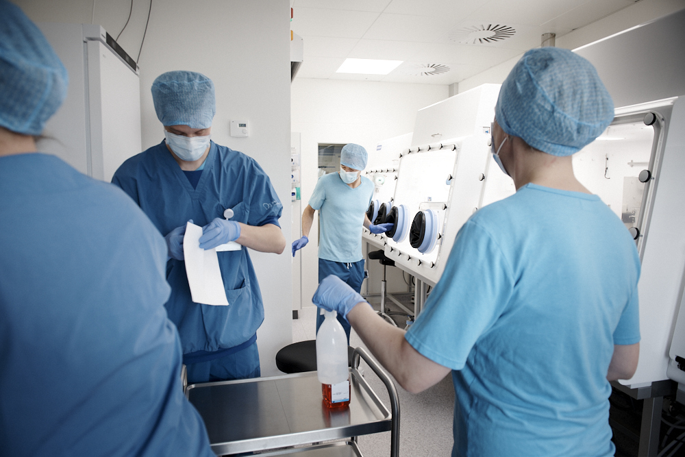 Laboratory personnel in a GMP-grade cleanroom environment using glove box isolators for stem cell culture. PL BioScience corporate image illustrating the safe manufacturing of ATMPs and the use of European-origin hPL (human platelet lysate).